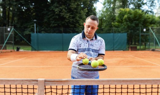 Teen boy with Down syndrome on tennis court