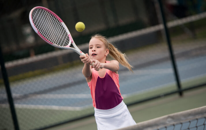 Girl playing tennis and hitting a ball with the racket