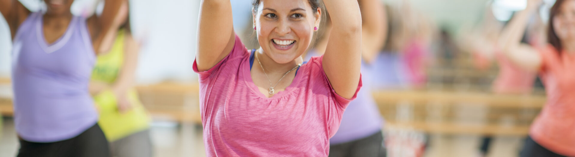 A multi-ethnic group of middle age women are dancing together in an aerobic fitness class.